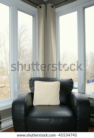 Black leather chair in corner of a room full of windows