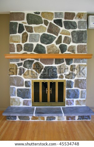 A multi colored stone fireplace with a wood mantle