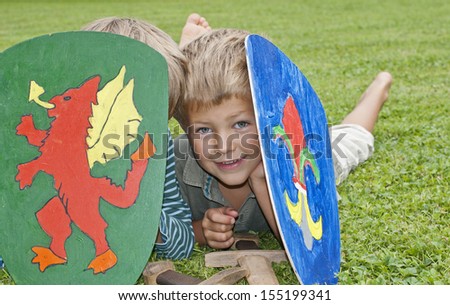 Cute, young boys playing with wooden swords and shields outside