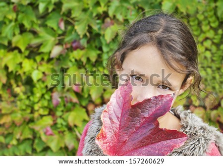 Pretty, young girl holding an autumn leaf to her face