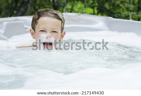 Cute young boy playing with foamy bubbles in a hot-tub