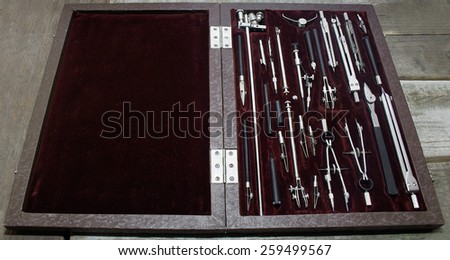 Case of drawing instruments. Old Case of drawing instruments laying on a wooden grunge table.