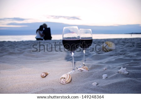 Romantic beach evening, two glasses of wine, shells, love couple on the background