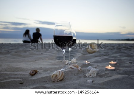Romantic beach evening, two glasses of wine, candles, love couple on the background