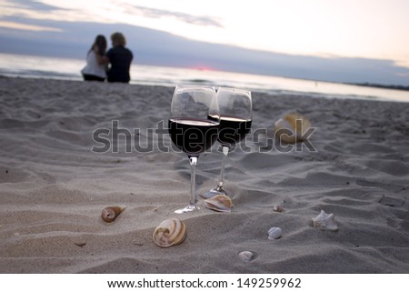 Romantic beach evening, two glasses of wine, candles, shells, love couple on the background