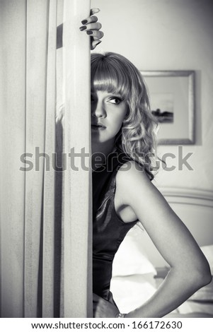 Beautiful girl hiding behind a curtain, in black and white