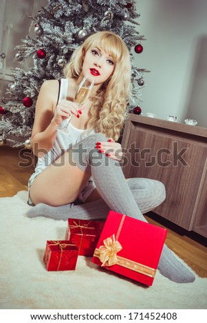 Christmas time, beautiful girl wearing a santa hat and holding a glass of sparkling wine