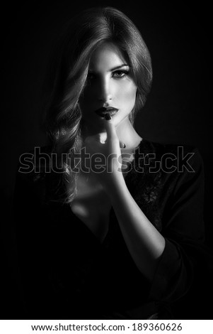Portrait of a beautiful young girl on black background, shadows and lightning, in black and white