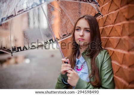 Beautiful teenager girl under the umbrella at a rainy day