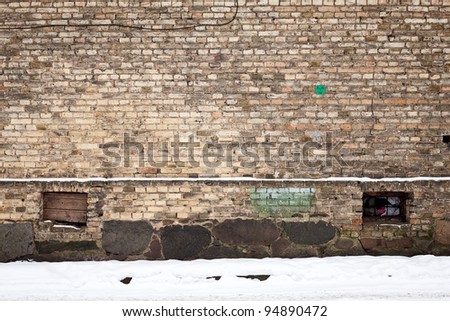 Old wall of stone bricks and a ground covered with snow