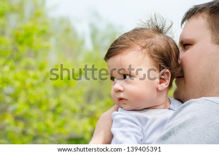 Happy young father with her baby looking off into distance in the park
