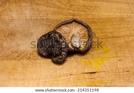 Close up of 2 dried shiitake mushrooms on a wooden chopping board