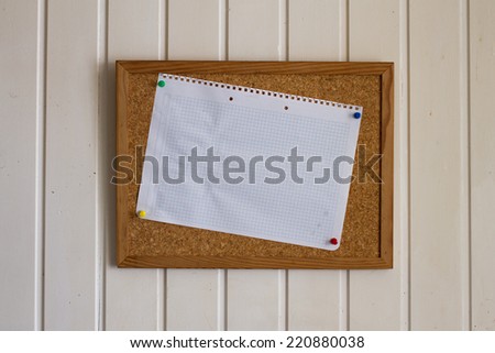 White checked piece of paper on cork board with white background