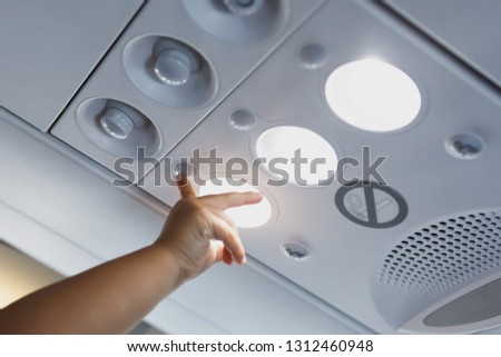 child hand pointing to the light lamp in airplane cabin