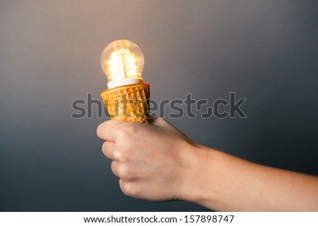 hand holding led lamp in ice cream cone, innovation concept