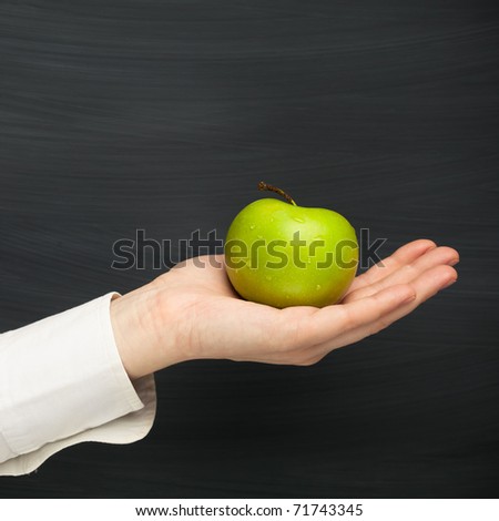 hand holding apple against blackboard background