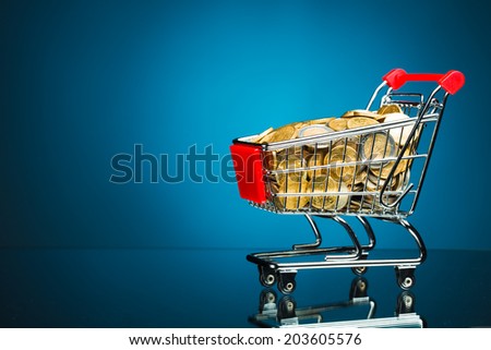 shopping cart full of money on blue background