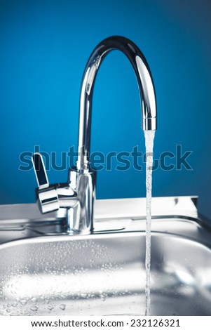 mixer tap with flowing water, blue background