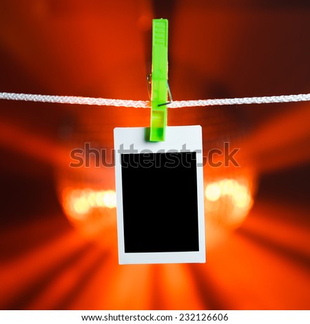 blank photo hanging on rope, orange lights background