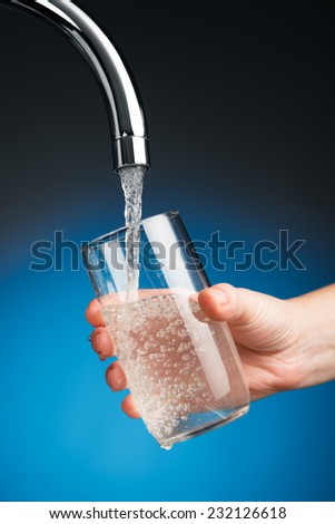 hand pouring a glass of water from mixer tap
