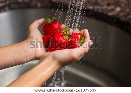 washing strawberries under a faucet