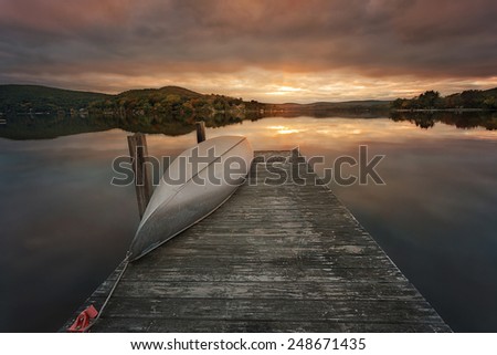 a canoe on a wooden dock on a lake during sunset