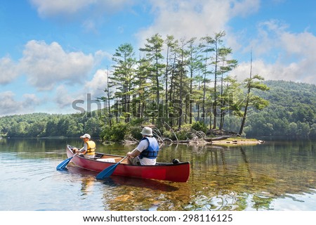 Father and child and the family dog canoeing on a lake on a beautiful, calm summer morning