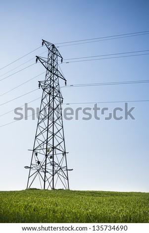 Electricity pylon, blue sky, green field