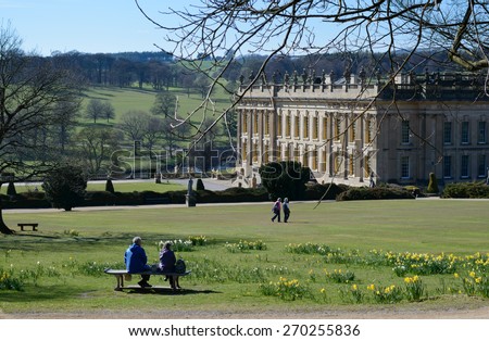 CHATSWORTH HOUSE, BAKEWELL, DERBYSHIRE, ENGLAND - APRIL 14: A middle aged couple sit on bench in gardens of Chatsworth House. At Chatsworth House, Bakewell, England on 14th April 2015.