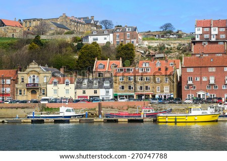 WHITBY, ENGLAND - APRIL 18: Whitby harbour, boats, and houses on Church Street, in Whitby, North Yorkshire, England. On 18th April 2015.
