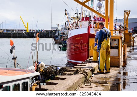 SCARBOROUGH, ENGLAND - AUGUST 26: Two male dock workers wearing oilskin bib n brace protective gear. In Scarborough, England. On 26th August 2015.