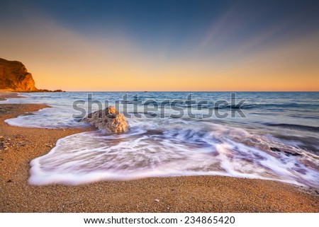 The sun sets illuminating the wet rocks and pebble beaches of the Jurassic Coast
