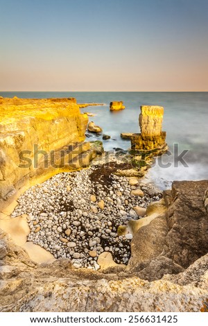 As the sun goes down over Portland Bill the sea calms and washes gently against the rocks