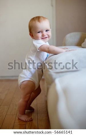 Baby standing up next to furniture