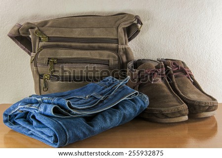 Still life with casual man, boots and bag on wooden table over grunge background.