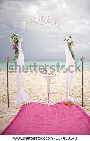 wedding arch on caribbean beach with decorated table and champagne