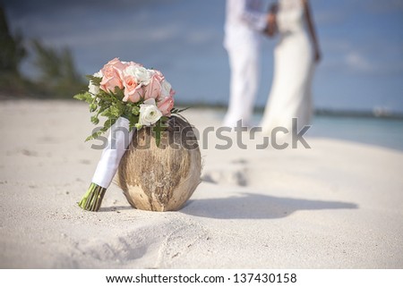 bride and groom on caribbean beach with coconut and wedding bouquet
