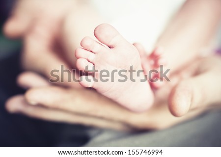 Little feet of a baby in a hands of a parents