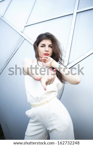 Brunette Woman with red lips standing near modern building hands outstretched