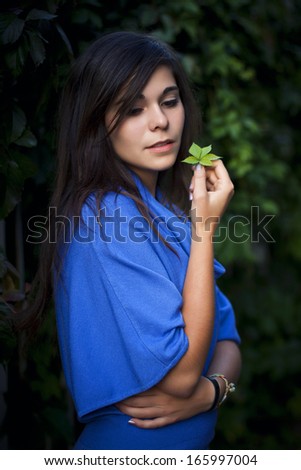 Brunette girl in the park in evening in blue dress with thoughtful look