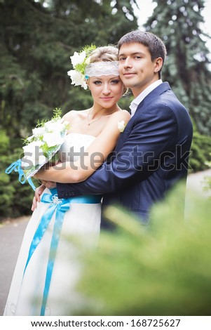 Young couple hugging in wedding gown. Bride holding bouquet with white lilies