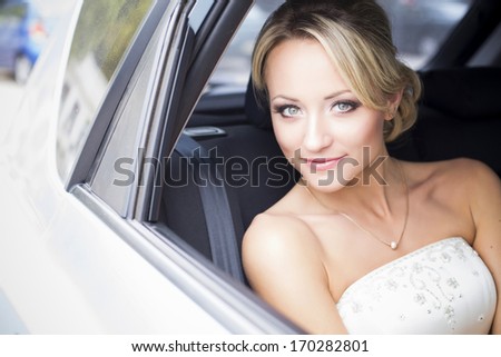 Beautiful bride sitting in a car in wedding gown