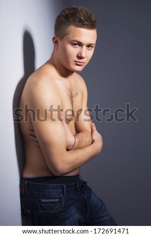 Shirtless handsome man with fit body lean against a wall indoor