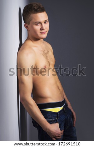 Shirtless handsome man with fit body lean against a wall indoor