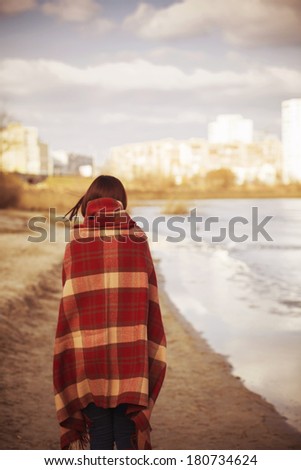 Brunette woman outdoors in check pattern plaid standing near the lake with her back on us. Copy space