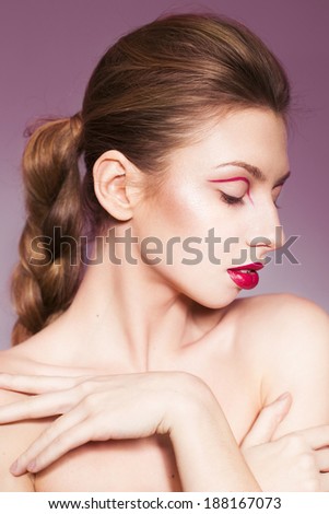 Beautiful brunette woman with red full lips and red lines on her eyelids and braid hairstyle and closed eyes