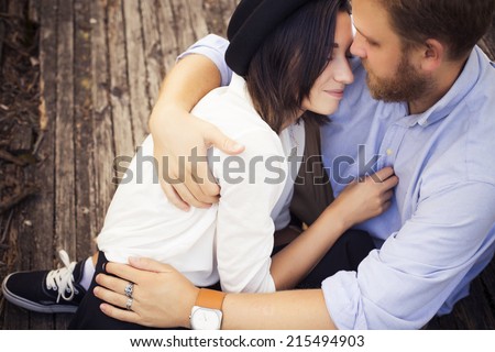 Beautiful hipster couple in love on a date outdoors in park having fun. Bearded red hair man. Brunette woman in black skirt and white blouse and black hat