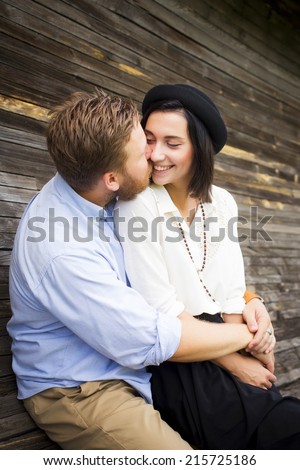Beautiful hipster couple in love on a date outdoors in park having fun. Bearded red hair man. Brunette woman in black skirt and white blouse and black hat