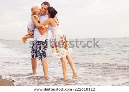 Family standing on a  sand seashore near sea looking at each other, relaxing on a vacation trip, looking on her husband. copy space
