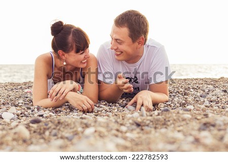 Couple sitting on a  sand seashore near sea looking at each other, relaxing on a vacation trip, looking on her husband. copy space